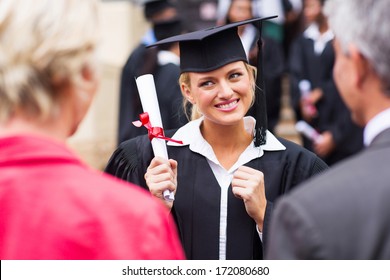 Excited Female College Graduate Looking At Parents