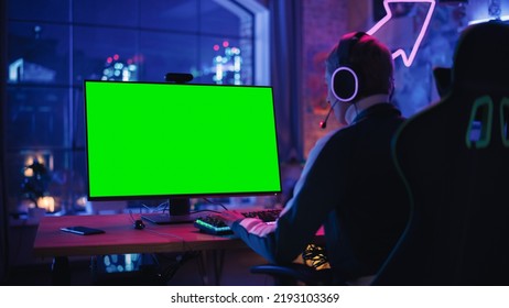 Excited Female Gamer Playing Online Video Game With A Mock Up Green Screen On Her Powerful Computer. Room And PC Have Colorful Neon Led Lights. Evening At Home In Cozy Apartment.