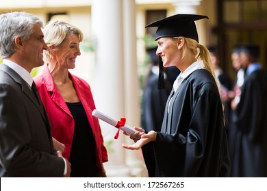 excited female graduate talking to parents on graduation day