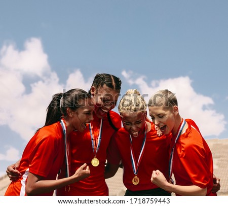 Excited female soccer players shouting in joy after winning the championship. Woman football team with medals celebrating victory.