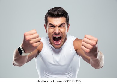 Excited fitness man shouting at camera over gray background