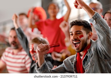 Excited football fans supproting Austrian national team in live soccer match at stadium. - Shutterstock ID 2137939711