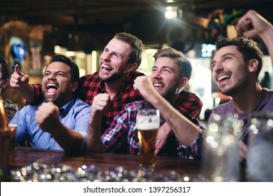 Excited Football Fans Watching Soccer In The Pub 