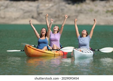 Excited friends celebrating vacation raising arms in kayaks in a lake