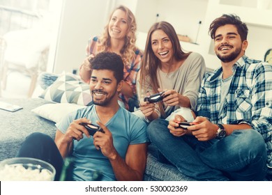 Excited friends playing video games at home.