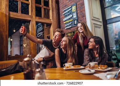 Excited Friends Taking Selfie With Smartphone Sitting At Table Having Night Out.