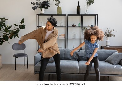 Excited Funny Black Mom And Curly Haired Daughter Kid Teaching Dance To Music In Living Room, Enjoying Activity, Exercising At Home, Laughing. Elder And Younger Sisters Having Fun At Home