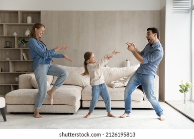 Excited Funny Parents And Sweet Happy Daughter Kid Playing Western, Making Gun Hand Gunshots, Dancing To Hip Hop Music In Living Room, Laughing, Having Fun, Enjoying Active Games Together