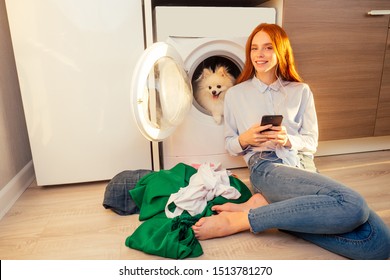 excited funny redhaired girl listening music with headphones,her adorable fluffy spitz inside the washing machine at home a pile of dirty clothes on the floor . - Powered by Shutterstock