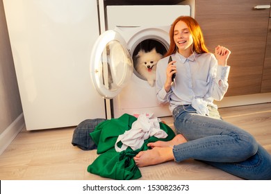 excited funny redhaired girl listening music with headphones,her adorable fluffy spitz inside the washing machine at home a pile of dirty clothes on the floor . - Powered by Shutterstock