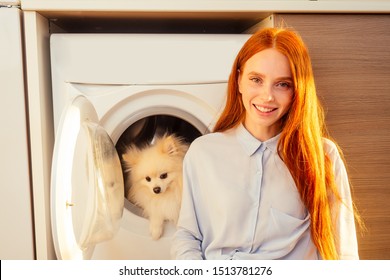 Excited Funny Redhaired Girl Sitting Next To Her Adorable Fluffy Spitz Inside The Washing Machine At Home . Spa Day For Pet Treatment Concept.