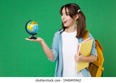 Excited Funny Young Woman Student In Basic Blue Shirt Backpack Hold Notebooks Earth World Globe Isolated On Green Color Background Studio Portrait. Education In High School University College Concept