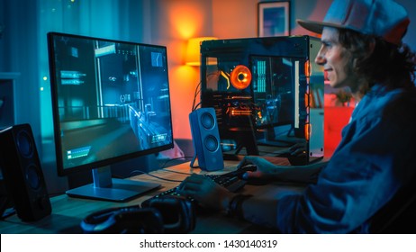 Excited Gamer Playing First-Person Shooter Online Video Game on His Powerful Personal Computer. Room and PC have Colorful Neon Led Lights. Young Man is Wearing a Cap. Cozy Evening at Home. - Shutterstock ID 1430140319