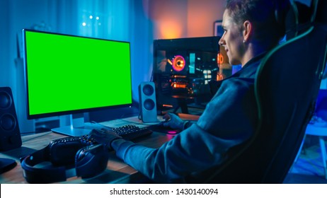 Excited Gamer Playing Online Video Game With A Mock Up Green Screen On His Powerful Personal Computer. Room And PC Have Colorful Neon Led Lights. Cozy Evening At Home.