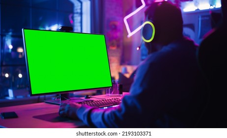 Excited Gamer Playing Online Video Game With A Mock Up Green Screen On His Powerful Personal Computer. Room And PC Have Colorful Neon Led Lights. Cozy Evening At Home In Loft Apartment.