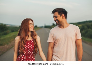 Excited girl and boy having their first date smiling and looking at each other as they walk along the paved road away from people. Front view. Smiling man - Powered by Shutterstock