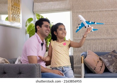 Excited Girl And Father Playing With Toy Airplane At Home