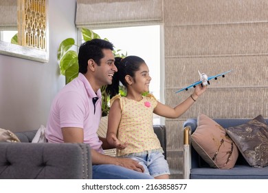 Excited Girl And Father Playing With Toy Airplane At Home