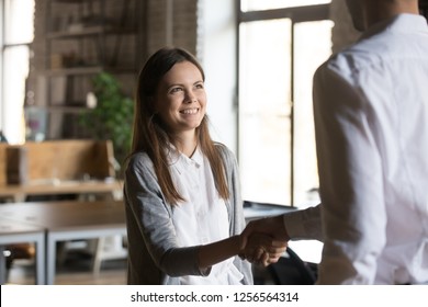 Excited girl intern handshaking executive manager getting hired rewarded, happy young employee proud to be promoted shake hands with boss congratulating successful worker, respect recognition concept