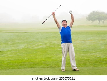 Excited golfer cheering on putting green on a foggy day at the golf course