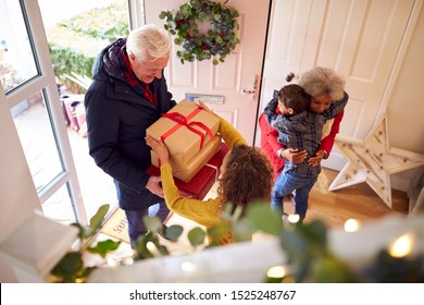 Excited Grandchildren Greeting Grandparents With Presents Visiting On Christmas Day