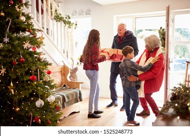 Excited Grandchildren Greeting Grandparents With Presents Visiting On Christmas Day