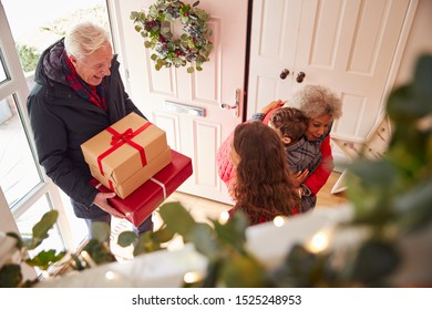 Excited Grandchildren Greeting Grandparents With Presents Visiting On Christmas Day