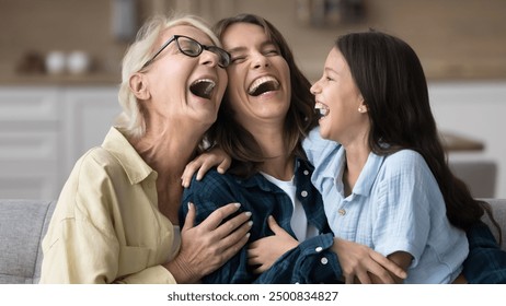 Excited grandma, happy young mother and cheerful kid girl laughing out loud with open mouth, having fun, telling jokes on home couch, tickling each other, enjoying family leisure. Banner shot - Powered by Shutterstock