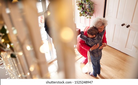 Excited Grandson Greeting Grandparents With Presents Visiting On Christmas Day