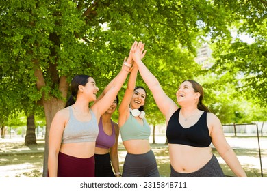 Excited group of diverse women doing a high five celebrating finishing their run together or exercises promoting body acceptance 