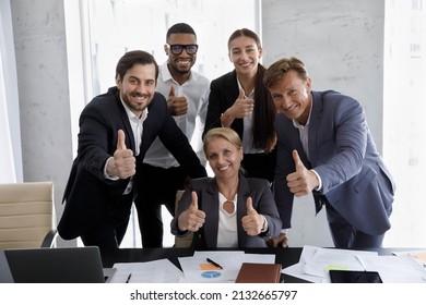Excited group of happy multiracial different ages business people managers coworkers employees looking at camera, showing thumbs up gestures, proposing offers, satisfied with corporate career.