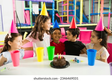 Excited group of kids laughing and having fun while celebrating a friend’s birthday party in the indoor playground - Powered by Shutterstock