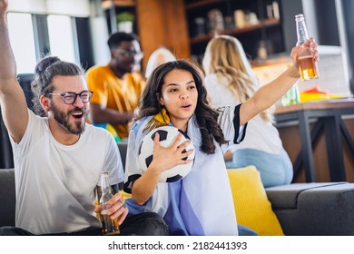 Excited group of people watching football, soccer sports match at home. Diverse Group of Sports Fans Wearing Team's Uniforms Watch Sports Game Match on TV - Powered by Shutterstock