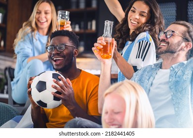 Excited group of people watching football, soccer sports match at home. Diverse Group of Sports Fans Wearing Team's Uniforms Watch Sports Game Match on TV - Powered by Shutterstock