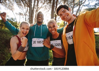 Excited group of runners celebrating their victory outdoors. Happy marathon runners after winning a race in the forest. - Powered by Shutterstock