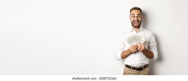 Excited Handsome Man Holding Money, Rejoicing Of Winning Cash Prize, Standing Over White Background