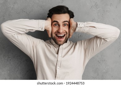 Excited Handsome Unshaven Guy Exclaiming And Grabbing His Head Isolated Over Grey Wall