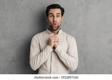 Excited handsome unshaven guy expressing surprise on camera isolated over grey wall - Shutterstock ID 1922897150
