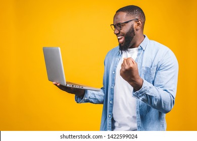 Excited Happy Afro American Man Looking At Laptop Computer Screen And Celebrating The Win Isolated Over Yellow Background.