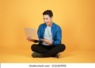 Excited Happy Asian Man Looking At Laptop Computer Screen And Celebrating The Achievement Isolated Over Color Background