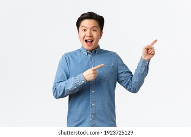 Excited And Happy Asian Man Making Big Announcement. Guy With Braces Smiling Amused And Pointing Fingers Upper Right Corner. Male Student Showing Courses Or Online Link, White Background