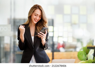 Excited happy Asian woman looking at the phone screen, celebrating an online win, overjoyed young asian female screaming with joy, isolated over a white blur background