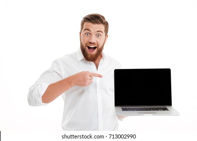 Excited Happy Bearded Man Pointing Finger At Blank Screen Laptop Computer Isolated Over White Background