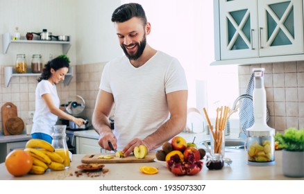 Excited happy beautiful young couple in love cooking in the kitchen and having fun together while making fresh healthy fruits salad - Powered by Shutterstock