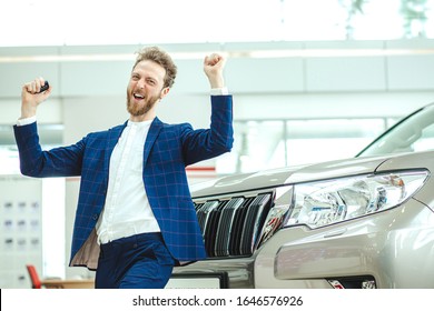 Excited Happy Caucasian Man After Getting New Car In Dealership, Joyful Cheerful Guy In Formal Suit Jump From Happiness With Keys From New Car