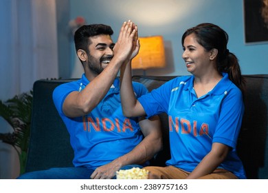 Excited happy couples Indian Team Jersey Celebrating win or victory while watching tv or television at home - concept of entertainment, sports fans and friendship. - Powered by Shutterstock