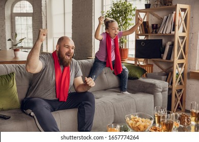 Excited, happy daughter and father watching football, soccer, basketball, tennis, hockey match on the couch at home. Fans emotional cheering for favourite national team. Sport, TV, championship. - Powered by Shutterstock