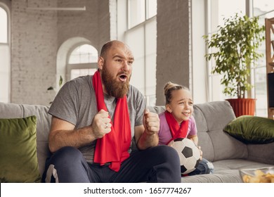 Excited, happy daughter and father watching football, soccer match on the couch at home. Fans emotional cheering for favourite national team. Having fun together, supporting. Sport, TV, championship. - Powered by Shutterstock