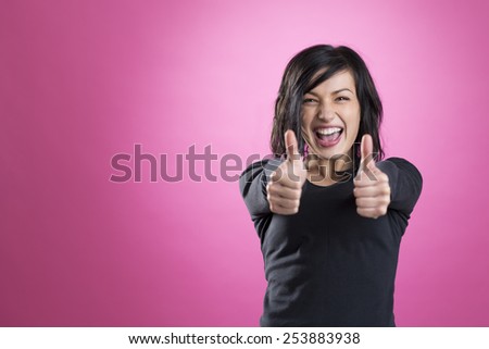 Excited, happy girl giving thumbs up showing success, isolated on pink background.
