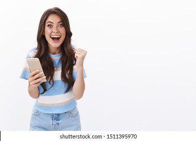 Excited Happy Triumphing Woman Hold Smartphone, Fist Pump And Smiling Enthusiastic, Receive Great Fantastic News Via Mobile Phone Text Message, Win First Prize, Winner Of Online Lottery